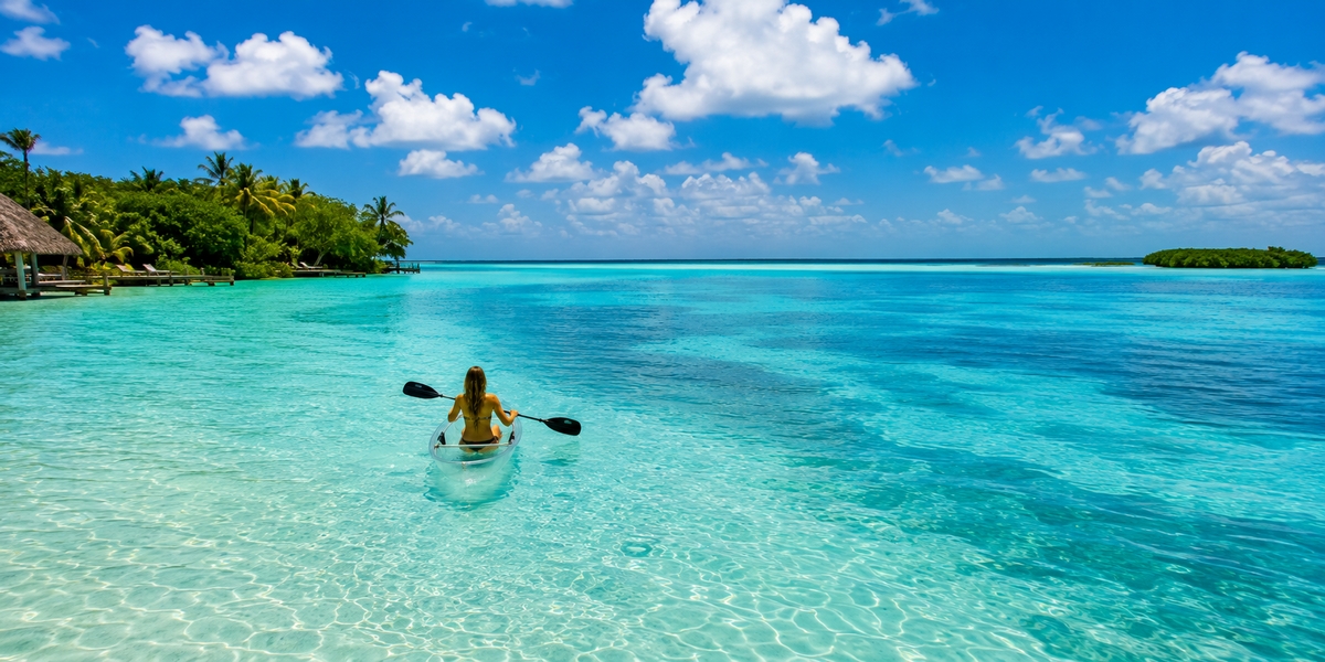 Shallow turquoise water over a pale limestone bed in Bacalar shading into deeper blue